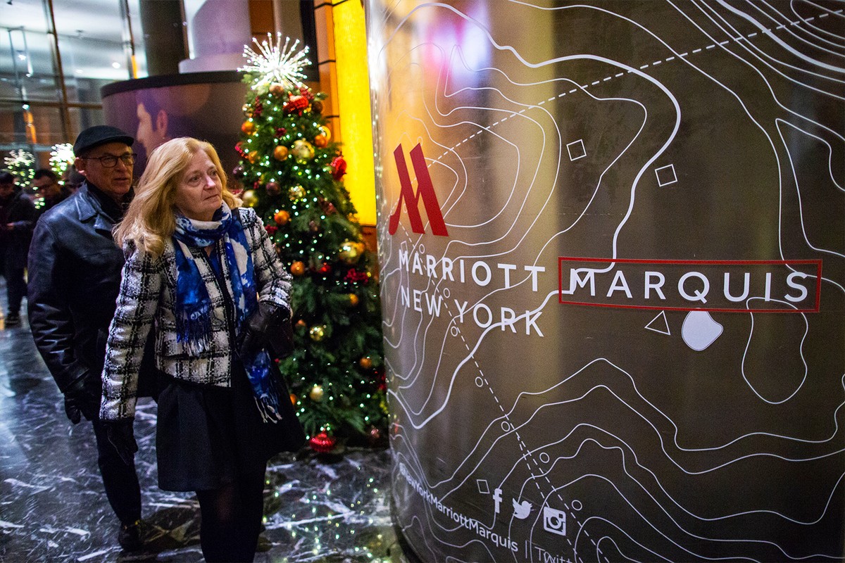 People walk past a Christmas tree through the lobby of the Marriott International hotel in Times Square.