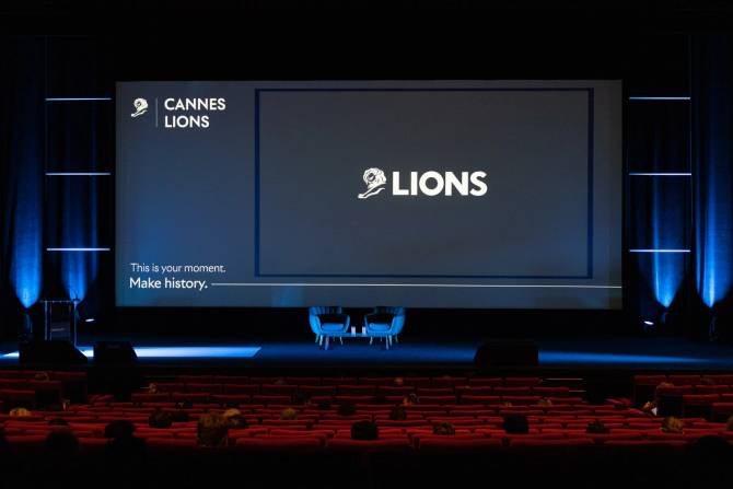 An image of the Cannes Lions logo on a black screen on the stage of an auditorium