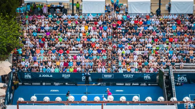 a stadium full of spectators in colorful garb watch a championship match at the PPA Tour: Atlanta Open