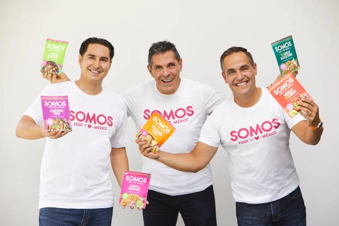 Three men wearing branded T-shirts holding up Somos products