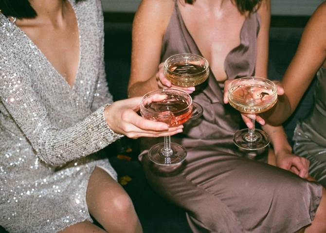 three women in dresses holding cocktails