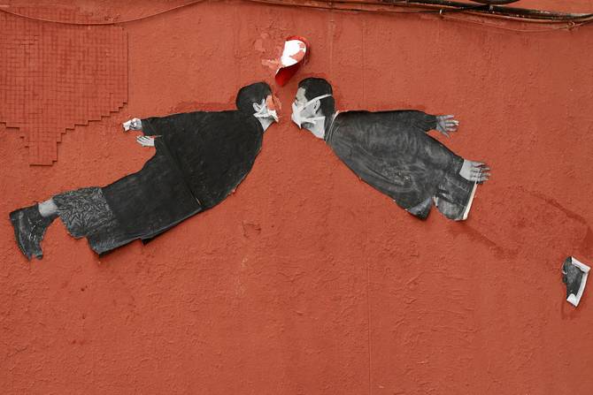 A mural of two people with face masks facing each other adorns a wall in Madrid