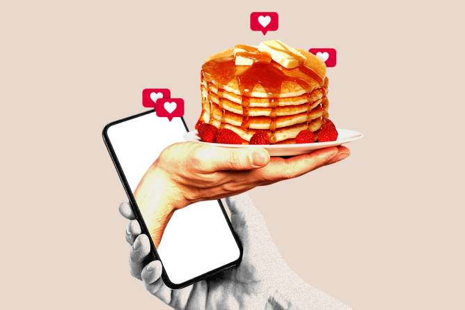 Hand with a plate of pancakes coming out of a phone