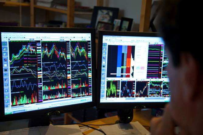 A trader looking at two stock screens