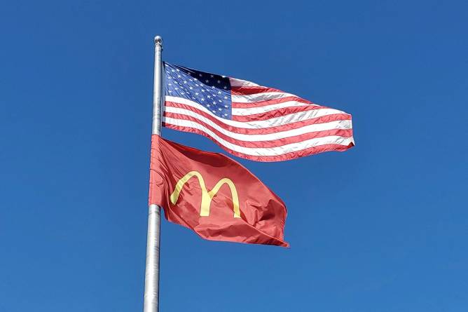 An American flag above a McDonald's flag on the same flagpole