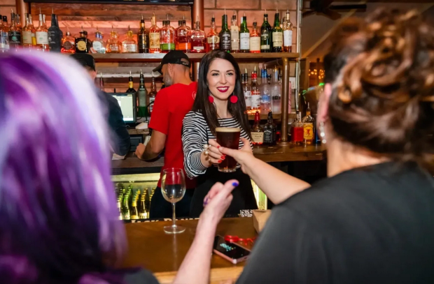 A bartender serves a drink at Residuals Tavern