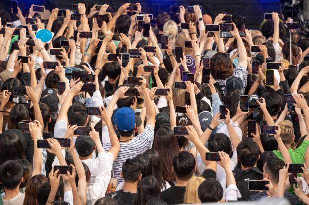 A crowd of people holding up cell phones.