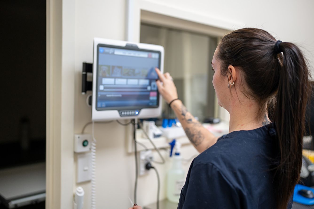 Young female nurse operating a touch screen in a medical clinic.