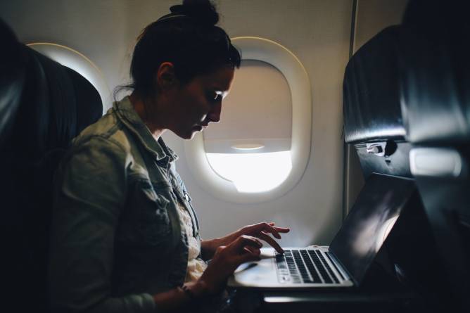 Woman using a laptop on an airplane.