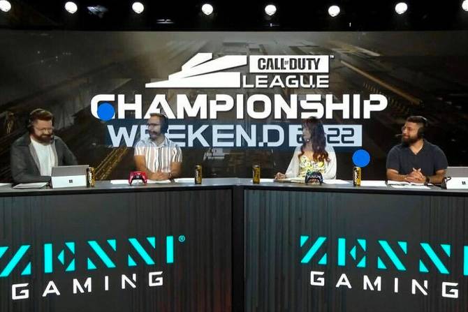 A photograph of four people broadcasting in a studio at a Call of Duty Championship event in 2022. The words Zenni Gaming are prominent on the set. 