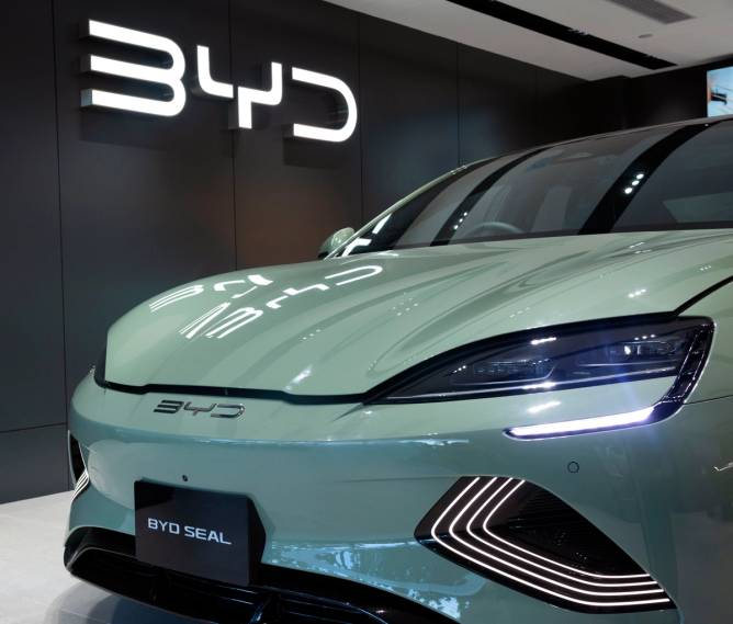 A BYD model in front of the company's logo in a showroom.