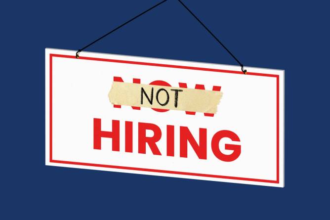 Now Hiring sign with piece of tape over "now" with "not" written on it.