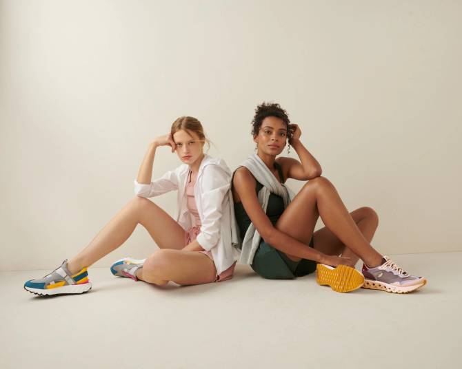 Two models sitting back to back and wearing running shoes