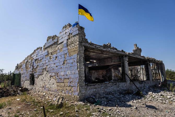 A Ukrainian flag above a destroyed building