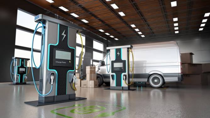 An electric commercial vehicle in a warehouse with charging equipment.