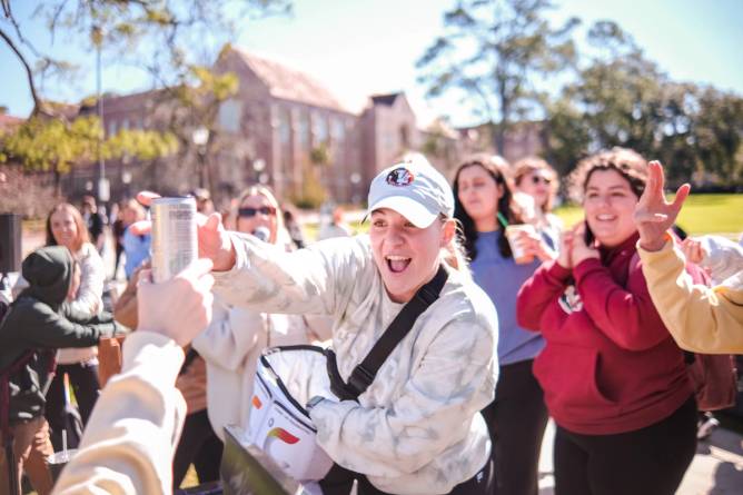 Caitlyn Stringfellow, a Florida State University student and Celsius University participant, hands out a can of the energy drink. 