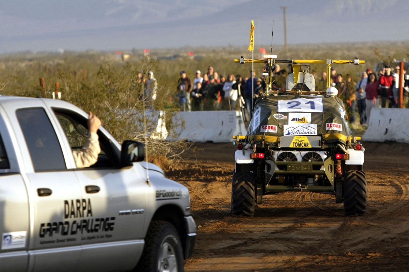 A member of the SciAutononics II team gives a thumbs-up gesture from the chase vehicle as they follow their autonomous vehicle from the starting line in a quest for a million-dollar prize at the DARPA (Defense Advanced Research Projects Agency) Challenge on March 13, 2004 near Barstow, California. 