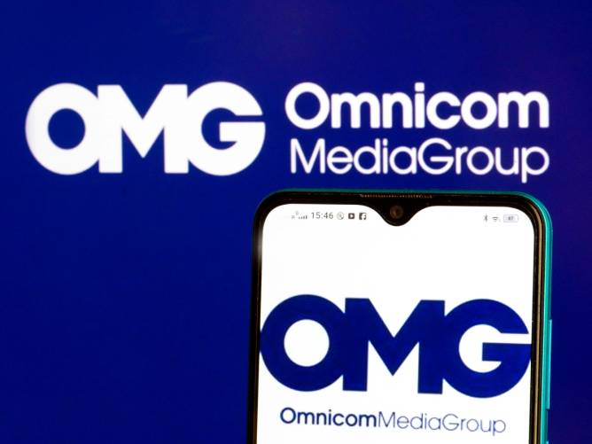 photo illustration Omnicom Media Group Holdings Inc logo is seen displayed on a smartphone and in the background.