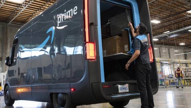 Image of Amazon delivery worker with Rivian electric truck inside warehouse