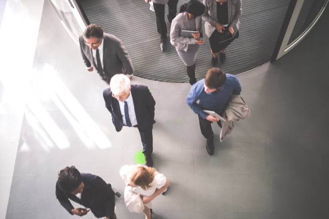 Around 7 or 8 people walking through a hallway in an office