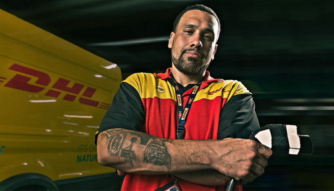 A portrait of DHL driver Tony Grimila posing with the electric-powered delivery truck he drives. 