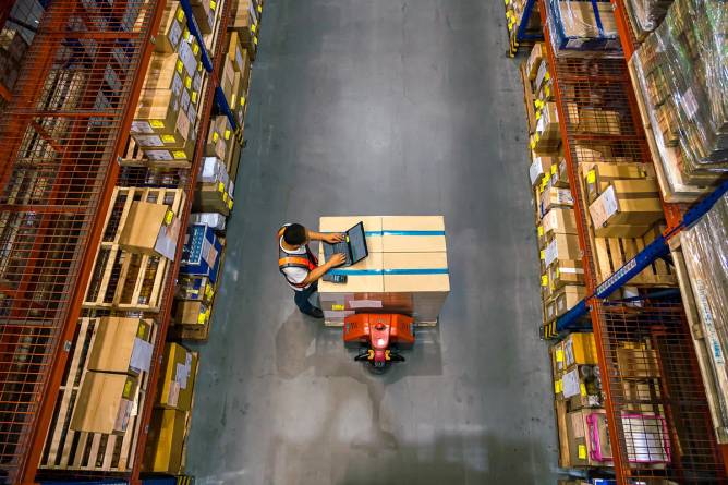 Birds eye view of a worker looking at computer in warehouse (Credit: Kmatta/Getty Images)