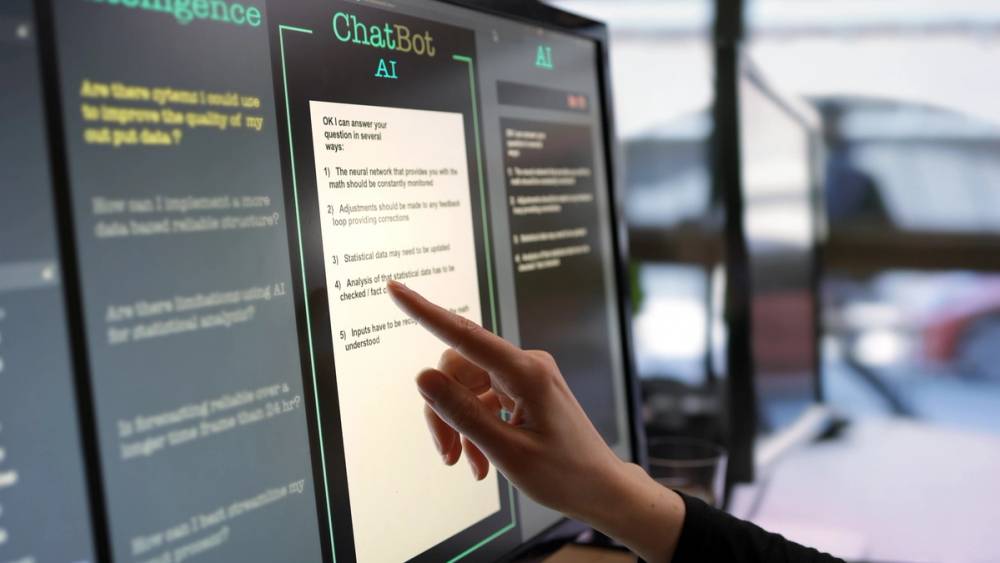 A person hovers their finger over a touch screen chat bot