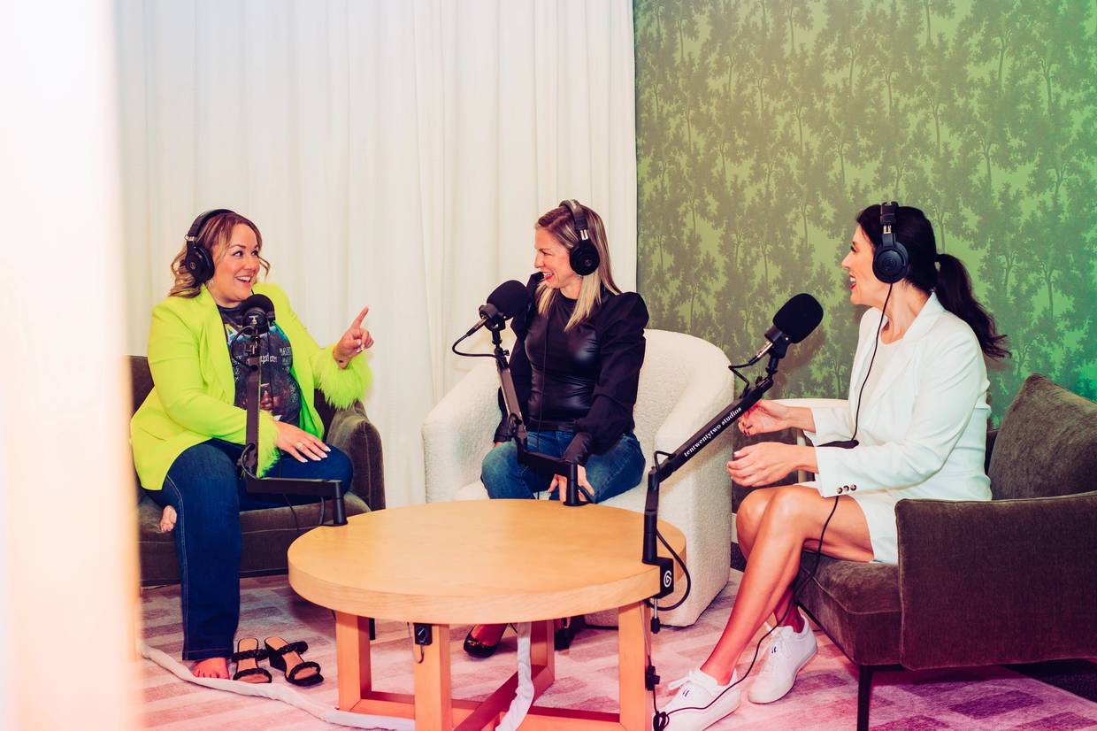 three women talking at microphones for podcast sitting in room