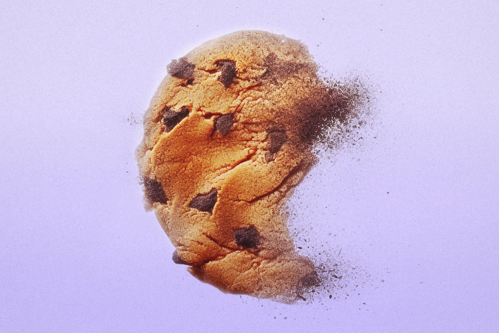 A chocolate chip cookie disappearing into thin air on a light purple backdrop