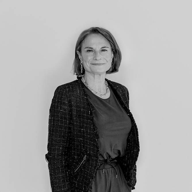 Black and white image of a white woman with chin-length hair, in a suit, standing up straight