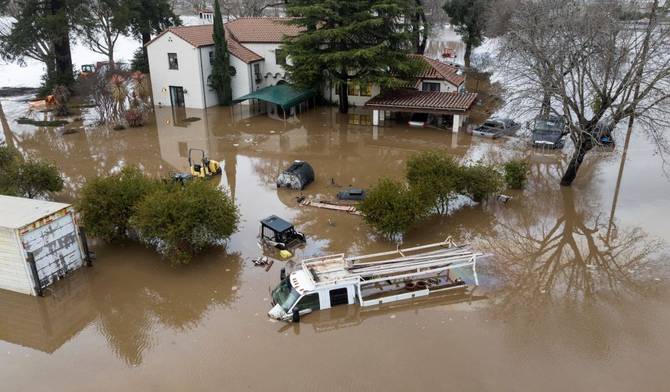 A house and cars partially submerged in flooding in California