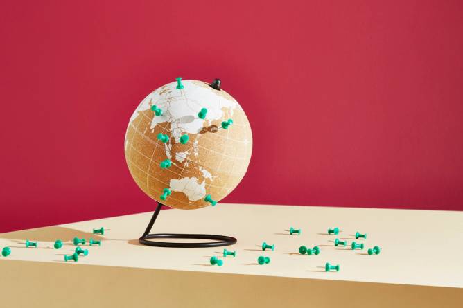 Illustrated tabletop world globe with pins marked on various locations.