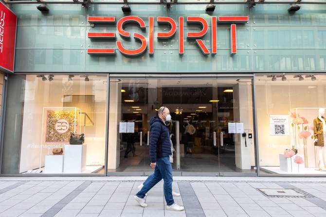 A pedestrian walks past an Esprit storefront. 