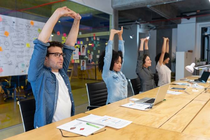 Workers stretch in a conference room.