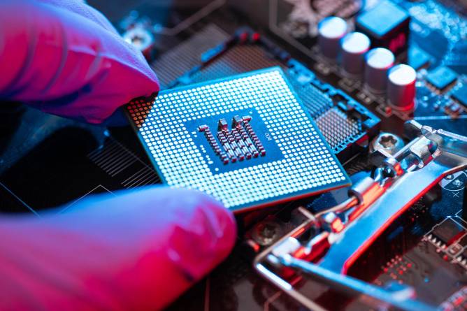 Two fingers holding a computer chip 