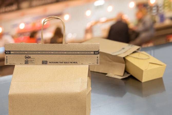 A paper bag with a handle has the top of it sealed by a bag-sealing cardboard product, Handle Cuff