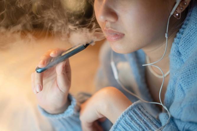 young person exhales e-cig vapor