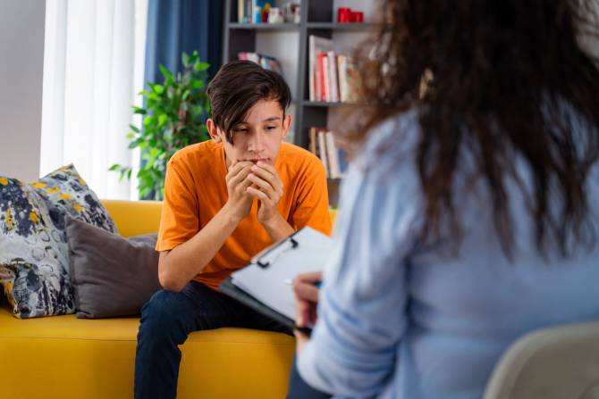 A female psychologist counsels a teenage boy.