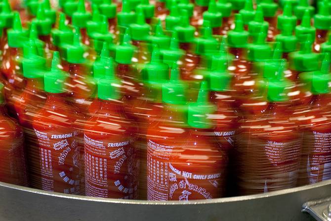 Sriracha bottles on a conveyer belt