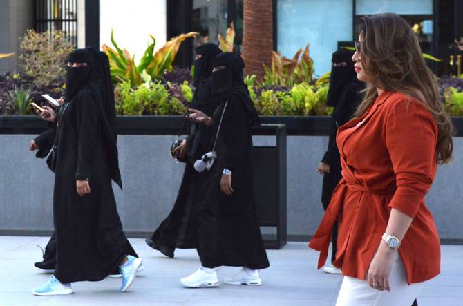 Saudi human resources professional Mashael al-Jaloud, 33, walks in western clothes past women wearing niqab, an Islamic dress-code for women, at a commercial area in the Saudi capital Riyadh