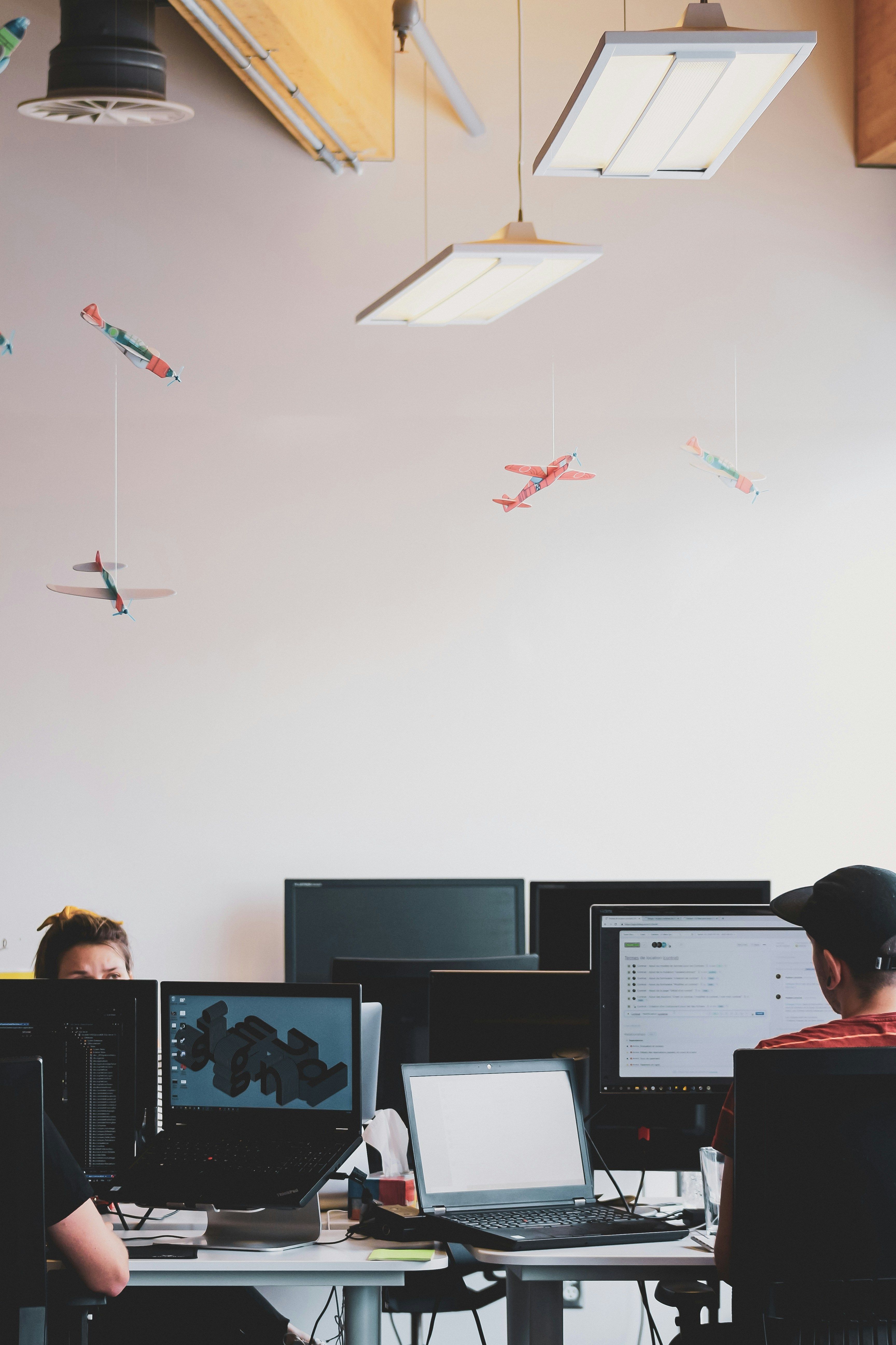 Multiple computer screens in office with workers.