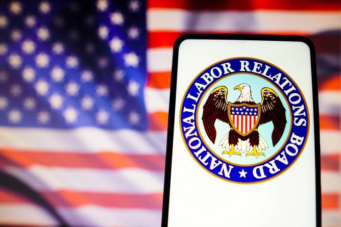 American Flag in the background; the national labor relations board emblem in the foreground on a smartphone