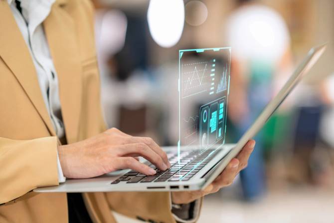 An individual wearing a blazer using a computer with a 3-D display in front of the screen.