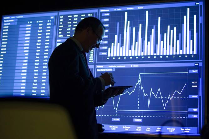Trader standing in front of stock screens