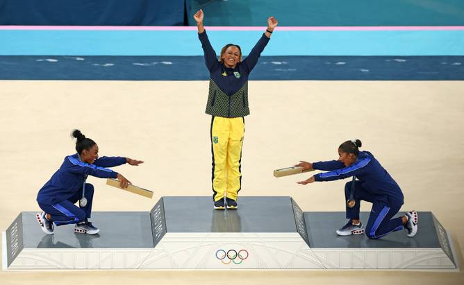 Gold medalist Rebeca Andrade (C) of Team Brazil, silver medalist Simone Biles (L) of Team United States and bronze medalist Jordan Chiles (R) of Team United States celebrate on the podium