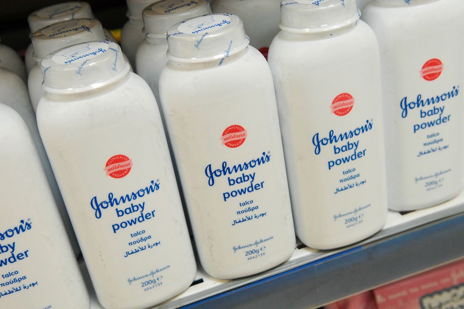 Fully stocked retail shelf, packaged bottles of Johnson & Johnson baby powder.