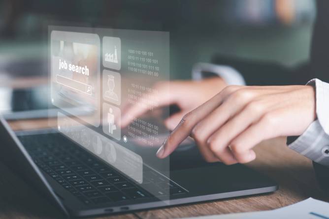 An image of hands over a laptop with a job search window on the screen.