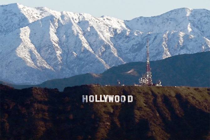 Snowy mountains fill the landscape behind the Hollywood sign.