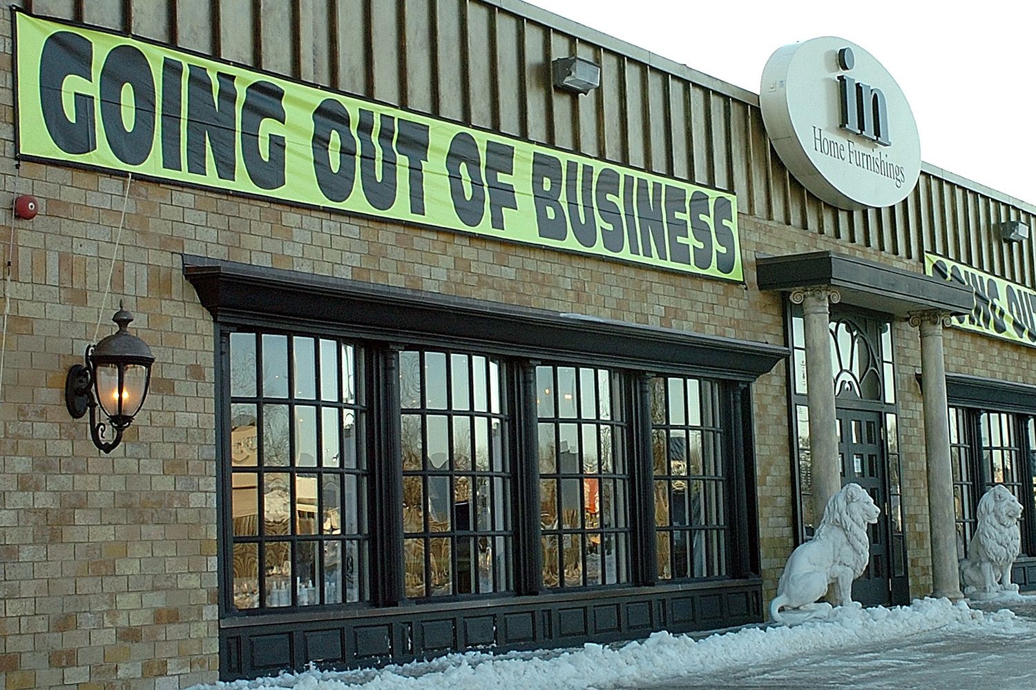 The facade of home furnishings store with large 'going out of business' banners covering the store front.