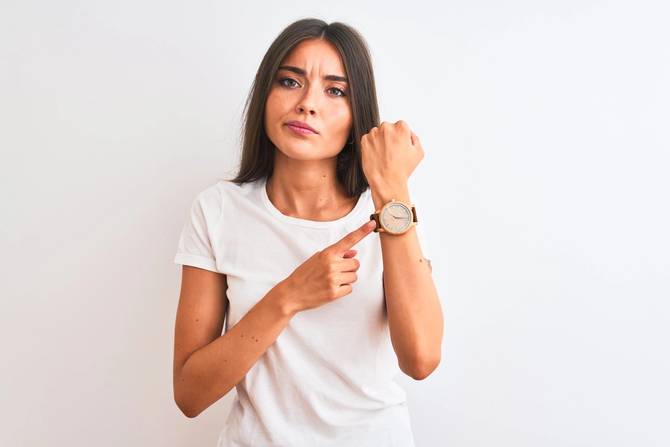 woman wearing t shirt pointing at wristwatch